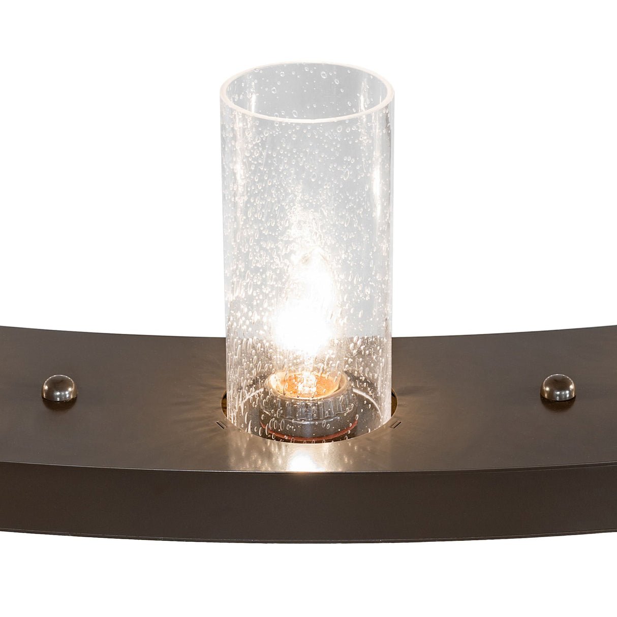 Close-up of seeded glass cylinder shade on chandelier with glowing bulb detail.