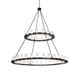 Lit view of two tier chandelier with seeded glass cylinders.