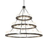 Illuminated chandelier with glowing frosted glass cylinders on three rings.