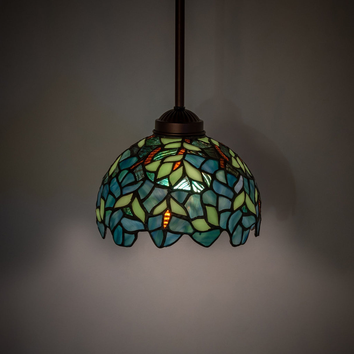 Illuminated view of the Nightfall Wisteria mini pendant, showcasing rich colors and intricate design.