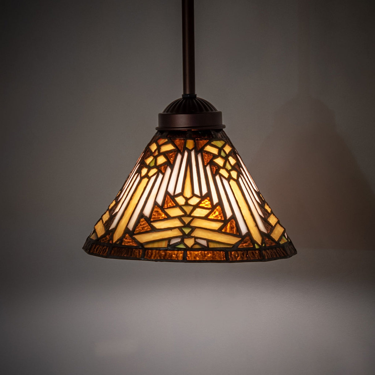 Illuminated Nuevo Mission mini pendant with warm amber and mahogany bronze tones.