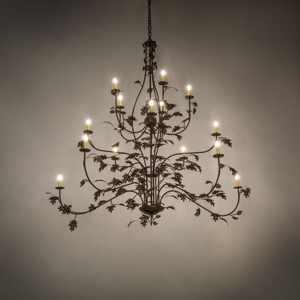 Oak leaf 15 light chandelier illuminated in an ambient room setting.