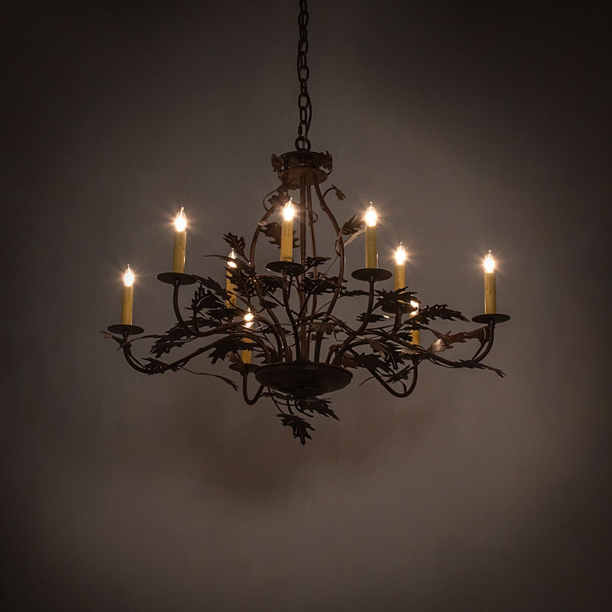 Oak leaf 9 light chandelier in ambient lighting with soft candle glow.