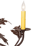 Close-up of candle socket showing yellow drip sleeve and leaf metalwork.