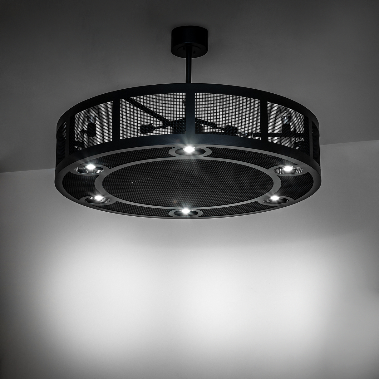 Paloma Golpe chandelier fan illuminated in a dark modern room.