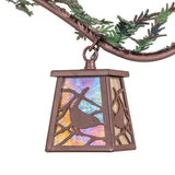Closeup of iridescent glass panel with pine branch cutout on chandelier lantern.