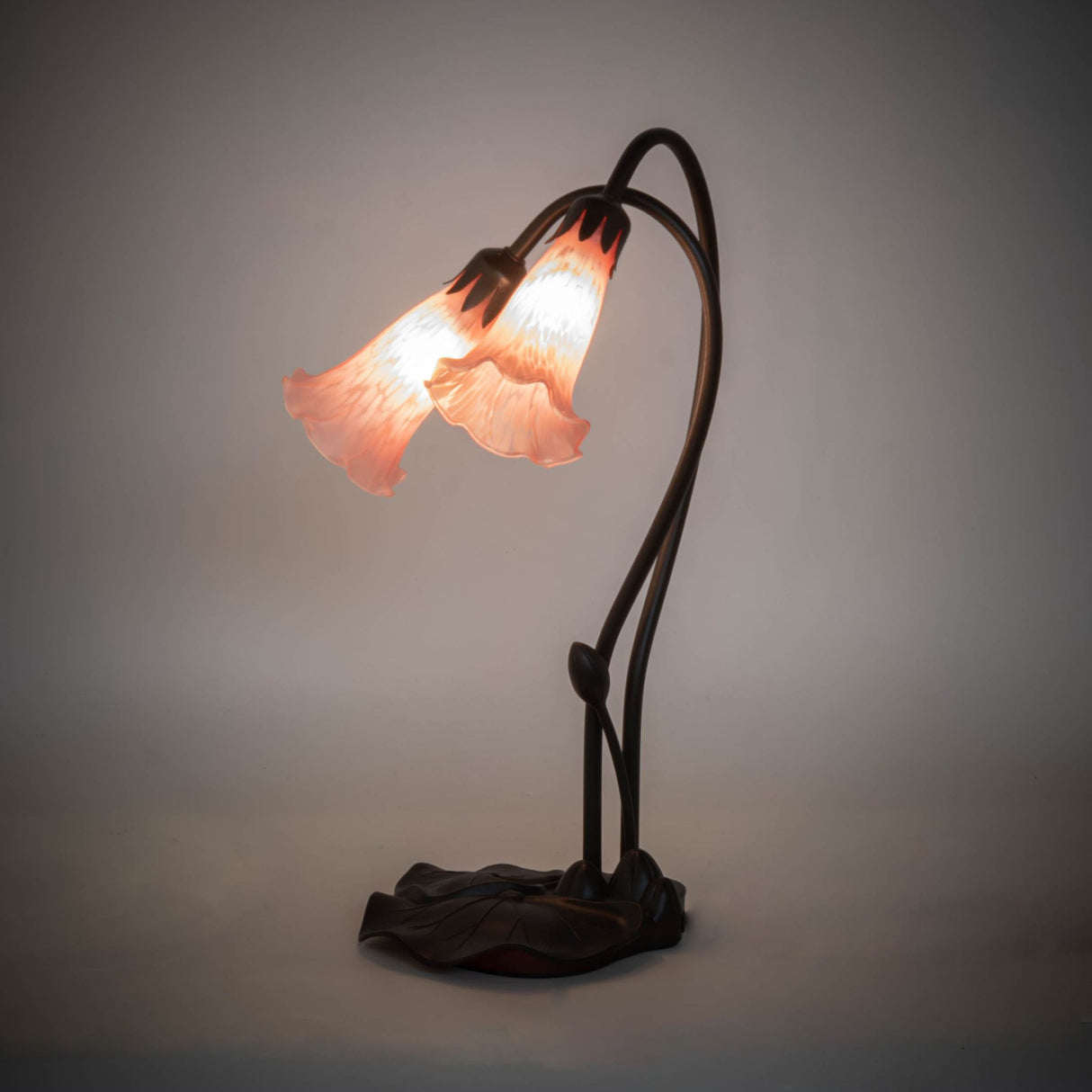 Illuminated view of the Pink Pond Lily accent lamp glowing with warm pink hues.