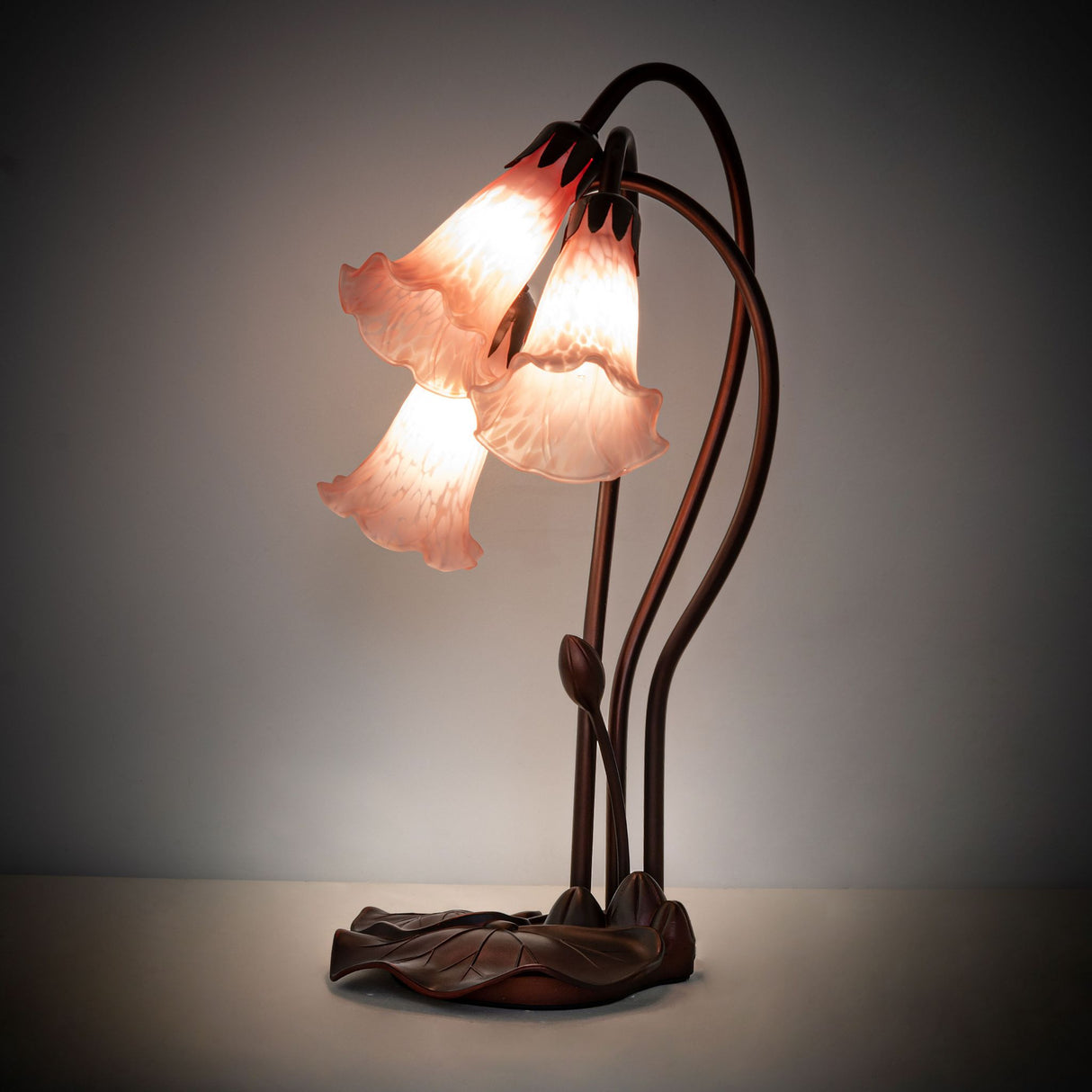 illuminated amber view of pink tiffany pond lily accent lamp with glowing petal pink shades.