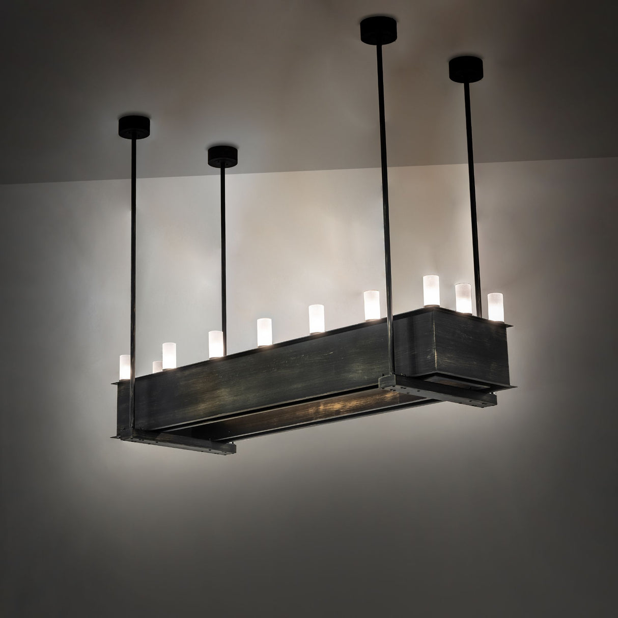 Quadrato oblong chandelier shown lit from the upper glass cylinders, creating an ambient ceiling glow.