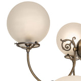 Close-up of frosted globe shade and curved arm in antique brass finish.