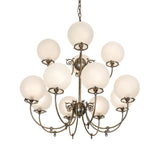 Lit view of gas and electric chandelier with frosted globe shades and antique brass finish.