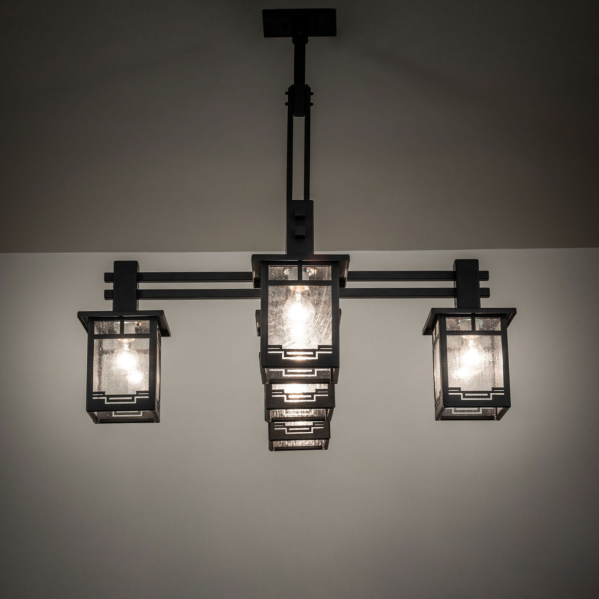 Roylance five light mission style chandelier illuminated with warm ambient lighting.