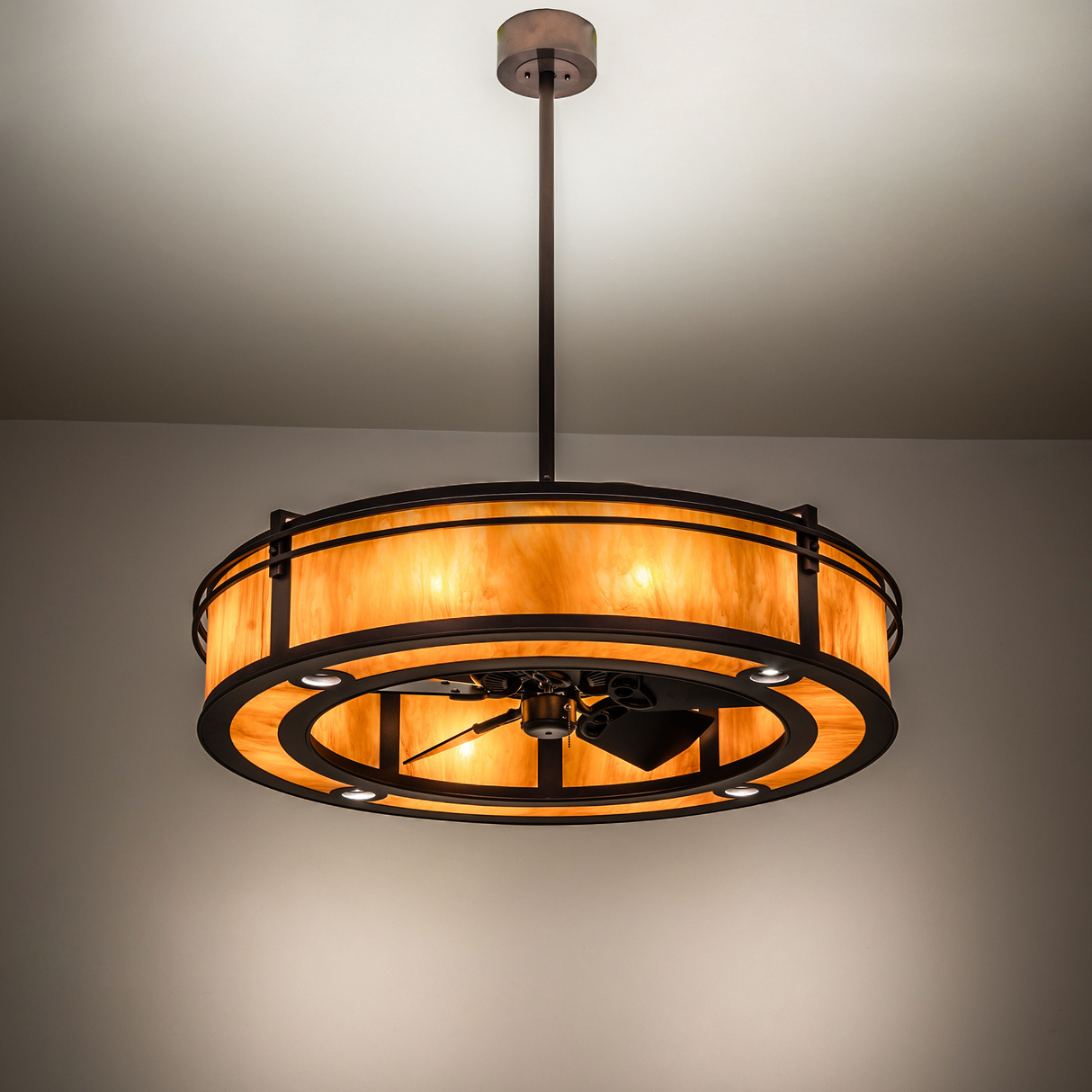 Ambient-lit view of Sargent chandelier fan glowing in bronze tones.