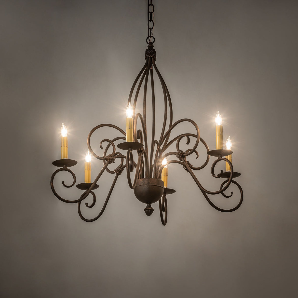 Ambient view of 6-light chandelier glowing in room setting, gilded tobacco finish.