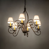 Ambient view of 6-light chandelier lit in room setting with warm glow and off-white shades.