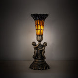 Illuminated view of stained glass pond lily twin cherub accent lamp glowing warmly.