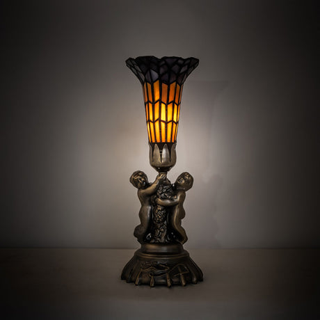 Illuminated view of stained glass pond lily twin cherub accent lamp glowing warmly.