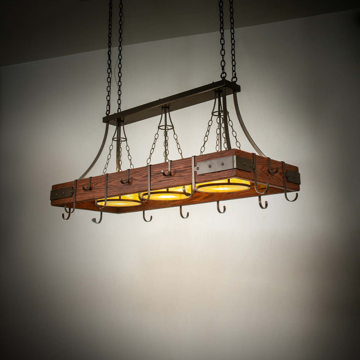 Steamboat 3-light pot rack chandelier glowing warmly in room setting.