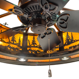 Closeup of fan housing and pull chain beneath illuminated pine forest pattern.