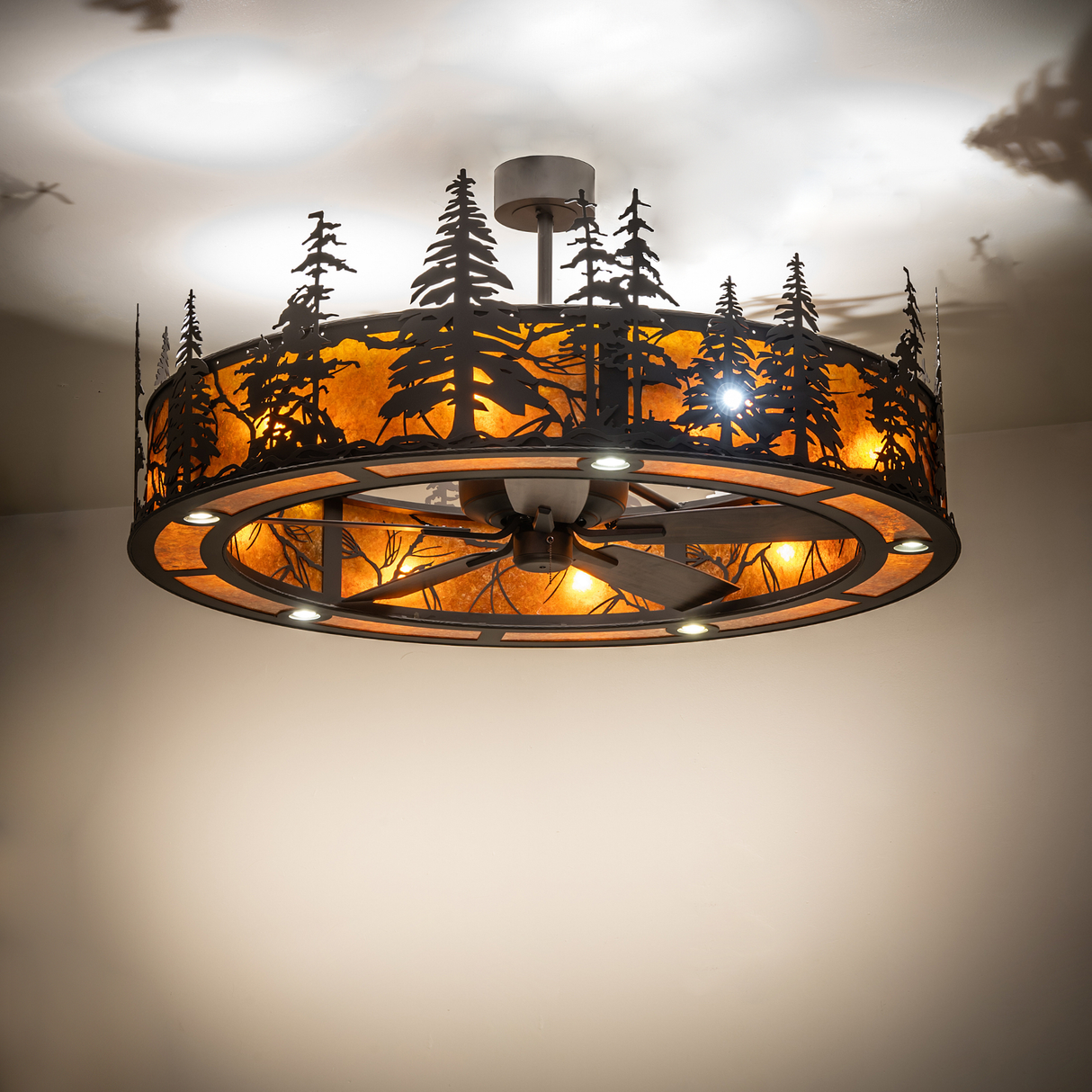 Illuminated Tall Pines chandelier fan glowing warmly with Amber Mica diffuser.
