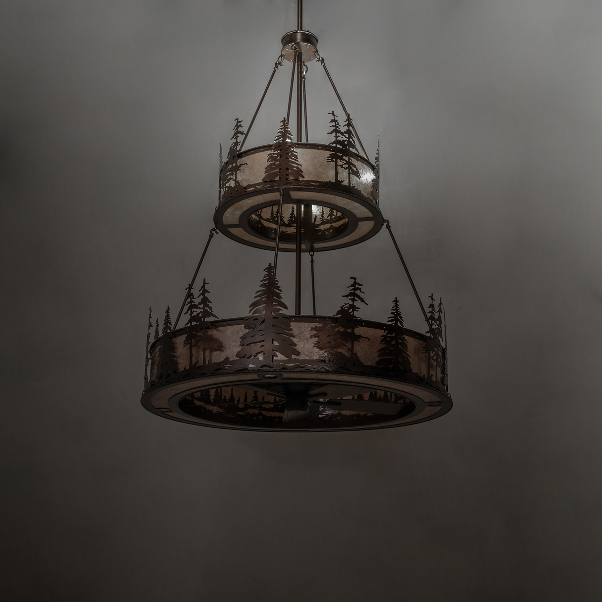Dimly lit Tall Pines chandelier showing forest silhouette details.