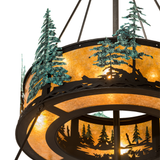 Close-up of illuminated upper tier with hand-painted pine tree silhouettes and amber mica diffuser.