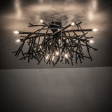 Ambient view of Thicket chandelier casting warm light with artistic branch-style metal design.