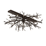 Lit view of chandelier, featuring branch-inspired metal arms in blackwash finish.