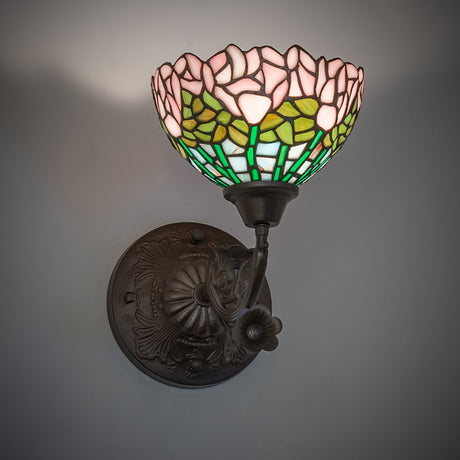 Wall-mounted Tiffany sconce illuminated, showcasing vibrant floral patterns.