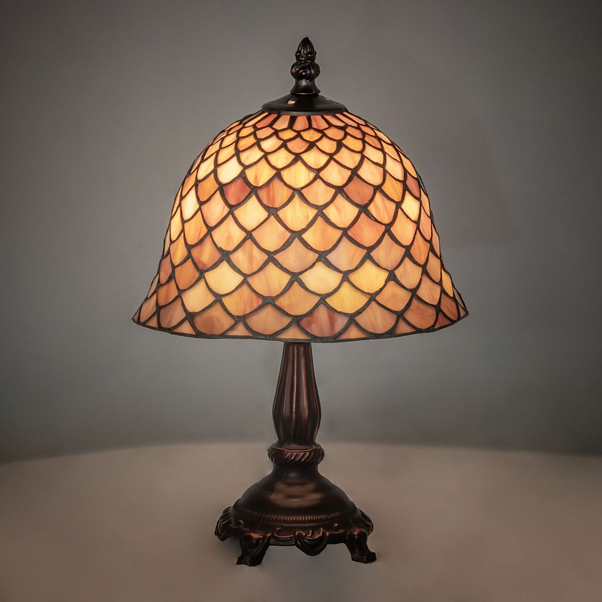 Illuminated view of the Tiffany Fishscale Mini Lamp glowing in warm amber hues.