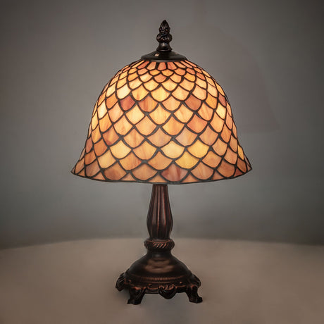Illuminated view of the Tiffany Fishscale Mini Lamp glowing in warm amber hues.