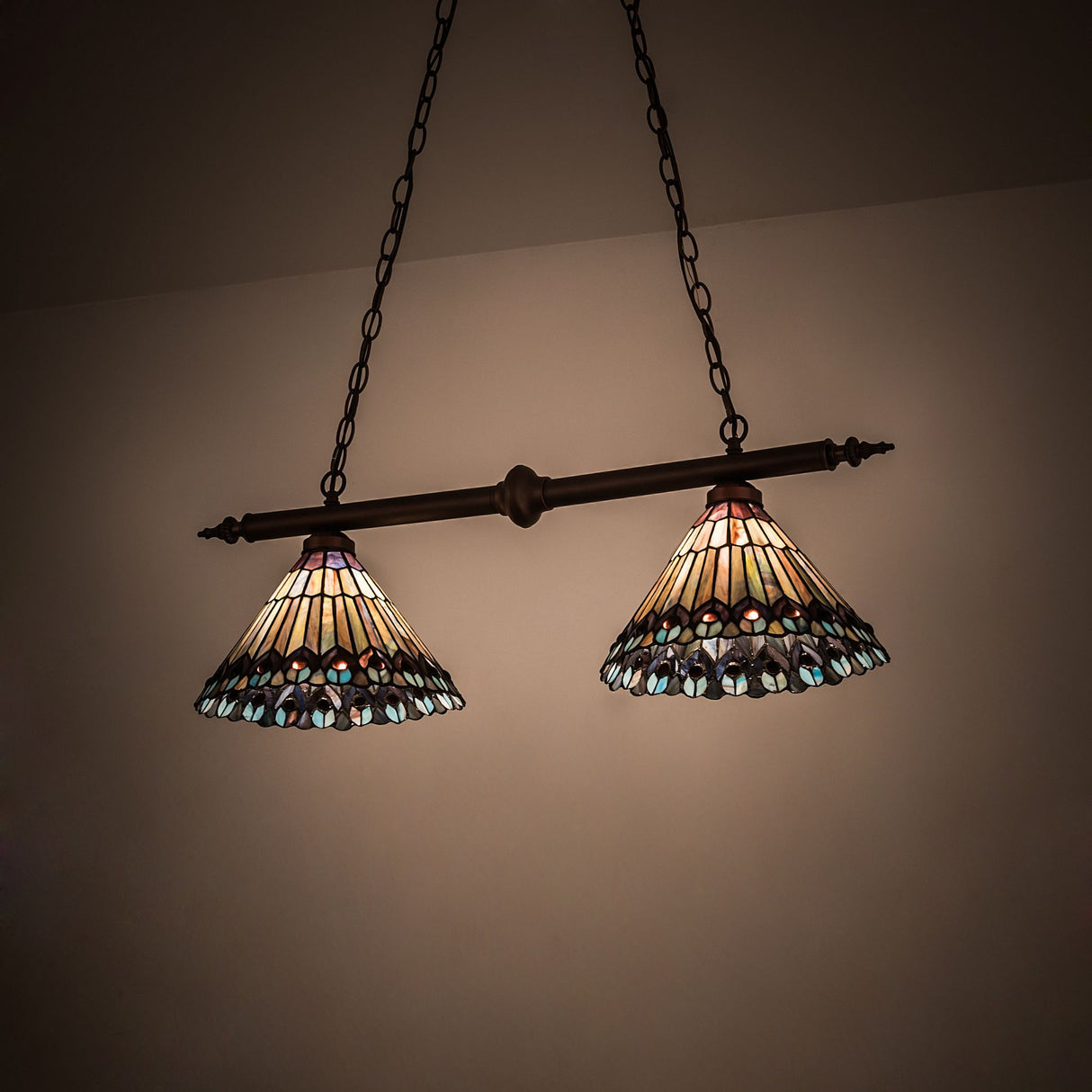 Illuminated view of Tiffany Jeweled Peacock 2-Light Island Pendant with intricate design.