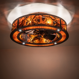 Whispering Pines chandelier fan casting warm amber glow on ceiling.