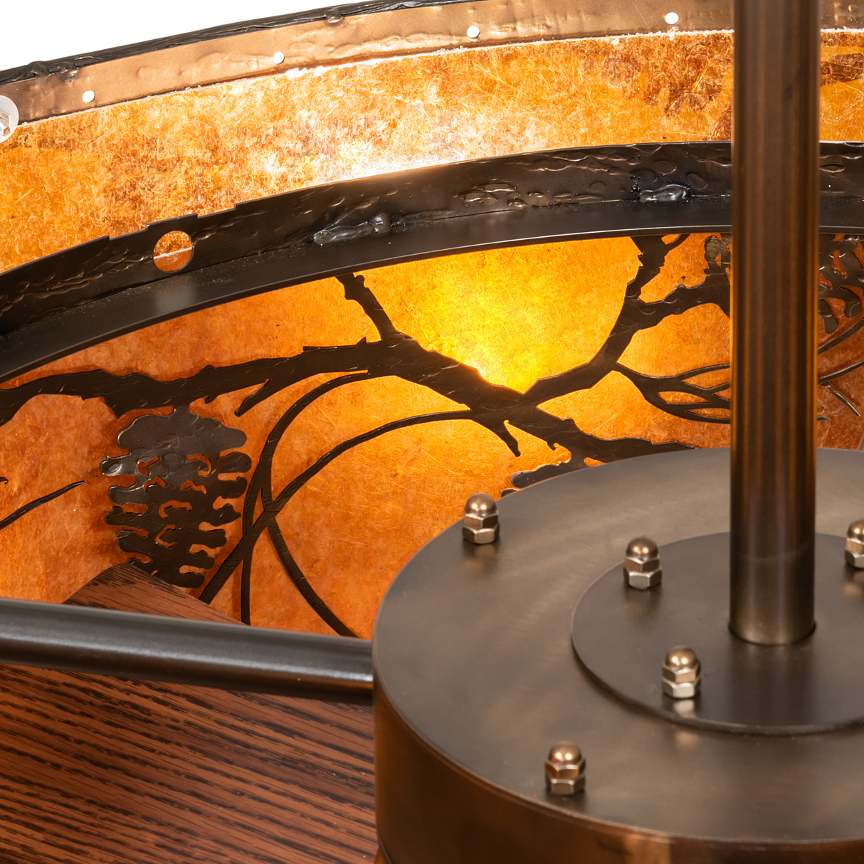 Close-up showing metal frame bolts and inner pine branch motif in warm light.