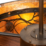 Close-up showing metal frame bolts and inner pine branch motif in warm light.