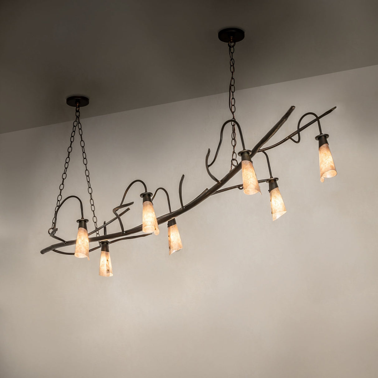 Winter Solstice oblong chandelier shown in ambient setting with warm illuminated mica shades.