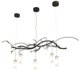 Lit view, glowing frosted glass cylinders suspended from branch-style metalwork.