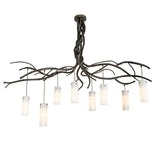Lit view of the chandelier showing warm light from eight cylindrical glass shades.